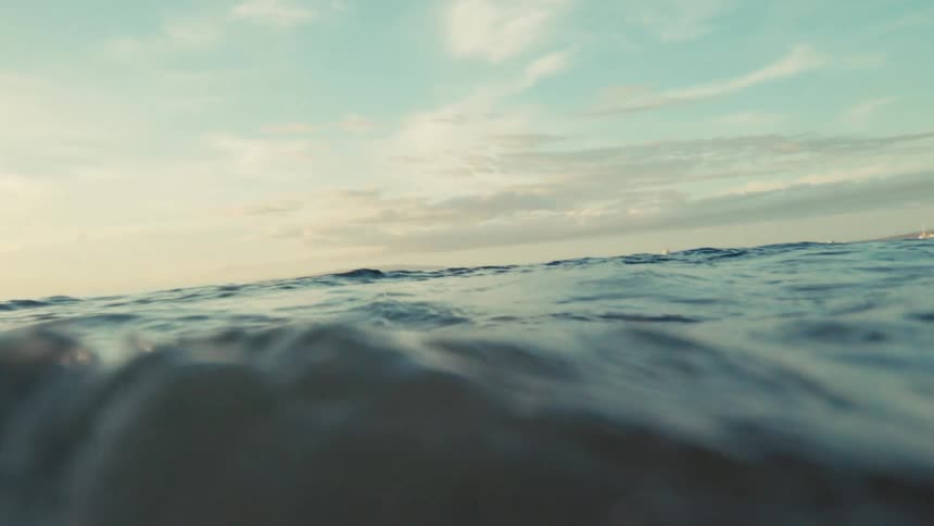 An immersive view from the ocean's surface slowly submerging into the murky, sandy water below