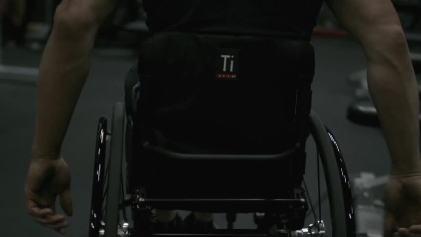 A man in a wheelchair wheels through a gym