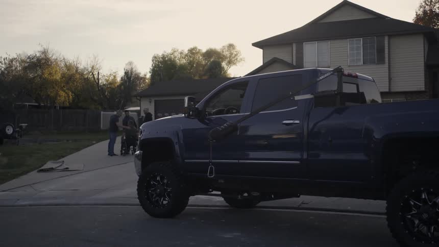Group of men stand in a driveway talking at sunset