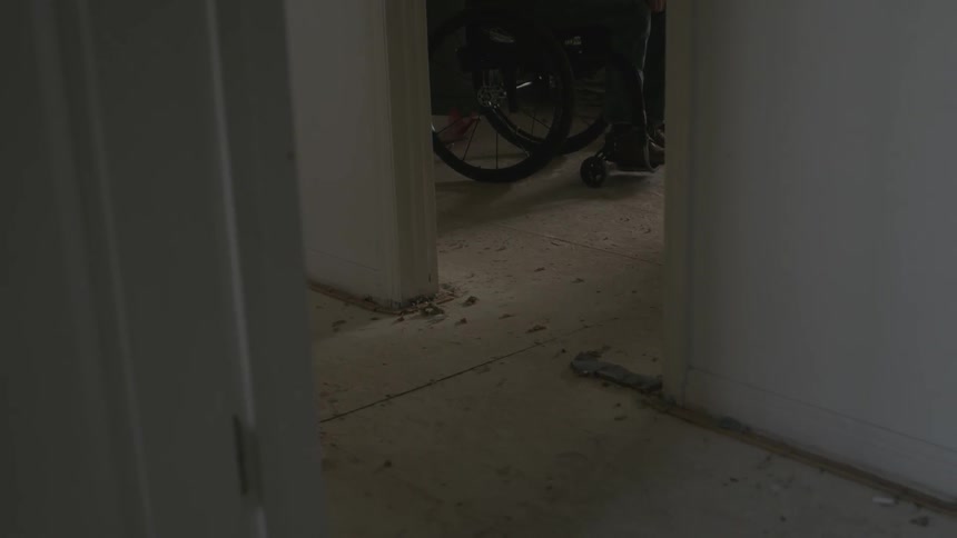 Person sitting in a wheelchair in a dim room