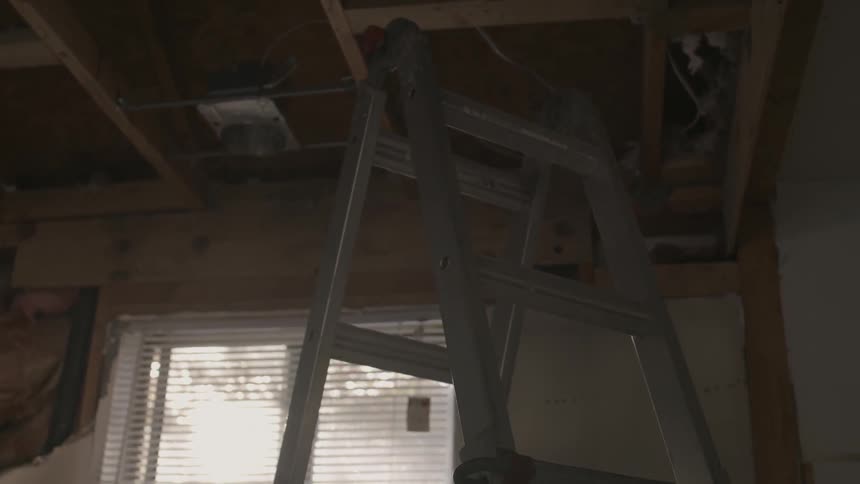 A ladder reaches up to an unfinished ceiling