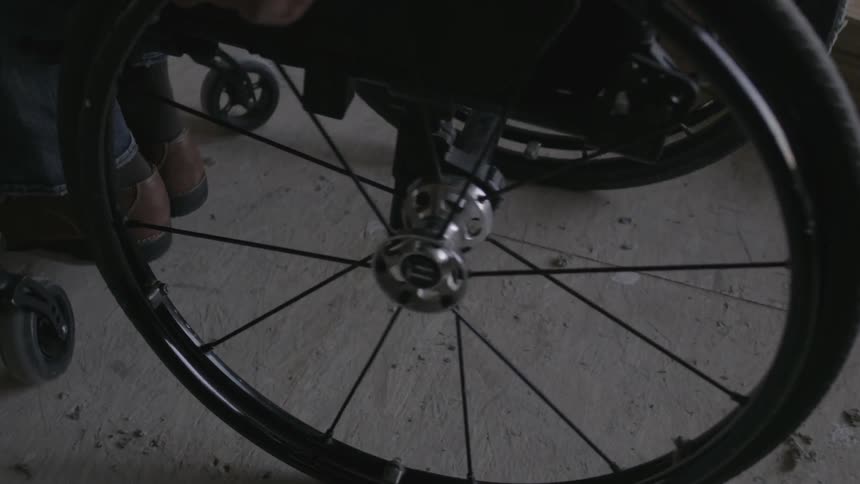 A man rolls in a wheelchair