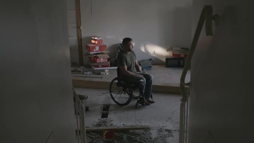 A man in a wheelchair sits in a room with construction supplies