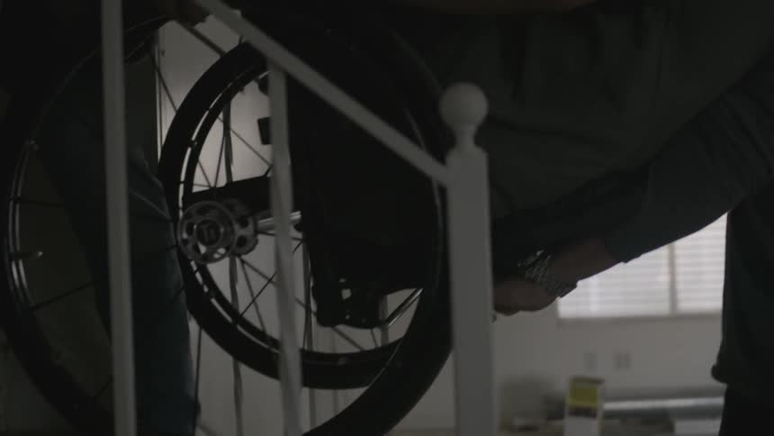 Man sitting in a wheelchair gets lifted up the stairs by two people