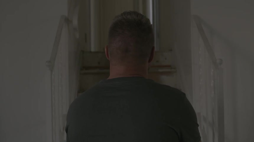 A man in a wheelchair is sitting staring up at a staircase