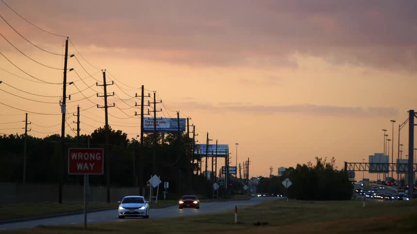 Cars driving down a highway at sunset