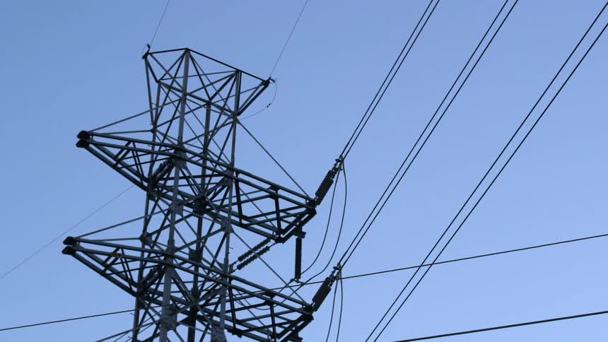 Power transmission tower and power lines in front of clear blue sky