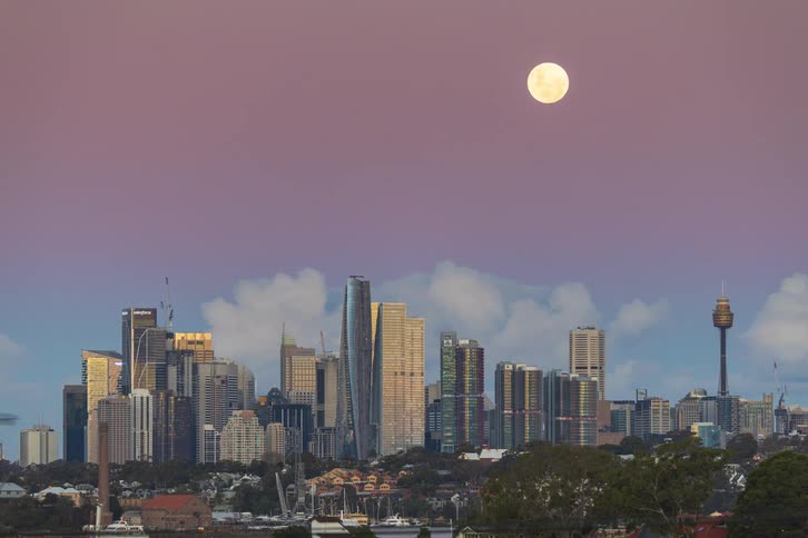A beautiful timelapse of the full moon setting over the Sydney city skyline as the sky transforms from a vibrant pink sunset to a clear blue morning