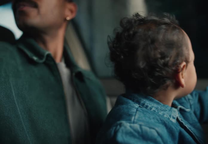 A doting father sits with his young son in the car, both captivated by the view outside the window