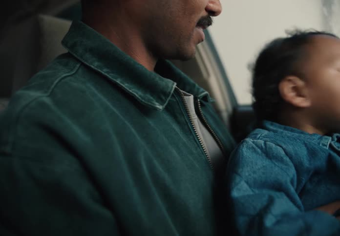 A loving father holds his curious baby boy on his lap while they sit together inside a car