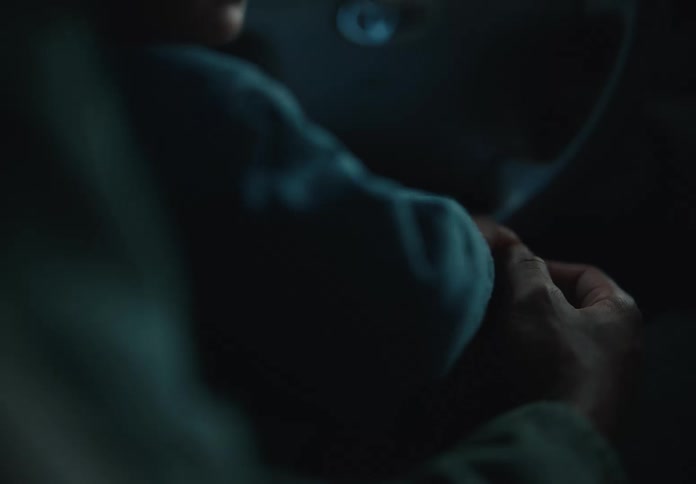 A loving parent holds their baby's hand as the child sits in the driver's seat of a car in a tender close-up