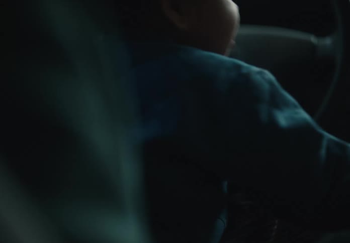 A close-up, tender moment as a parent gently holds and plays with their baby's tiny hand inside a car