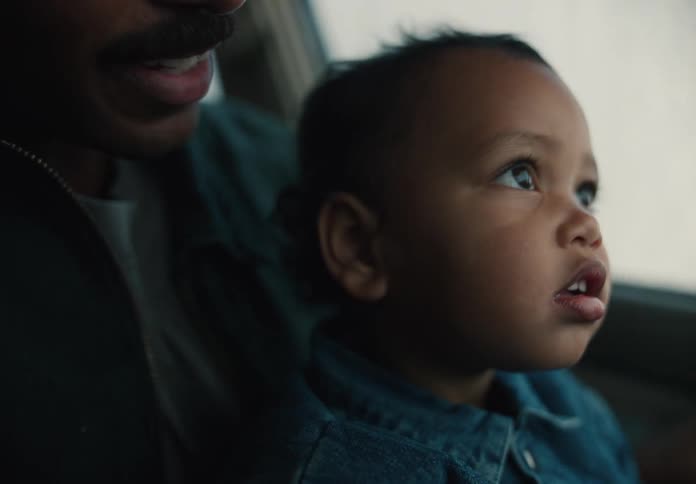 Close up on a cute toddler's face as he looks out the car window with wonder while sitting next to his father