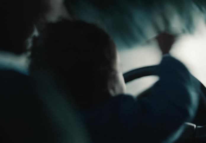 An over-the-shoulder shot reveals a delighted baby watching the car wash experience with their parent