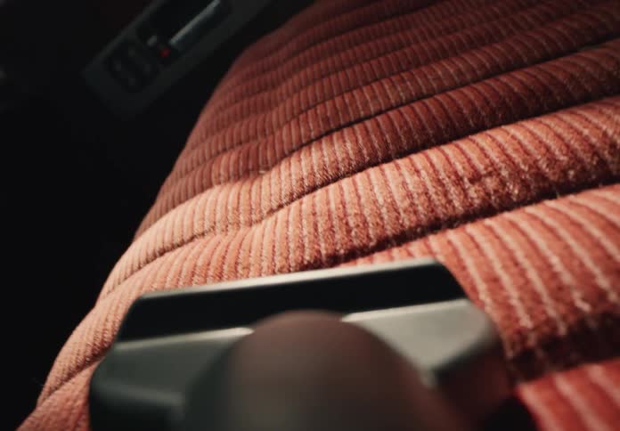 A detailed close-up shot of a vacuum cleaner nozzle cleaning the textured red fabric of a car seat