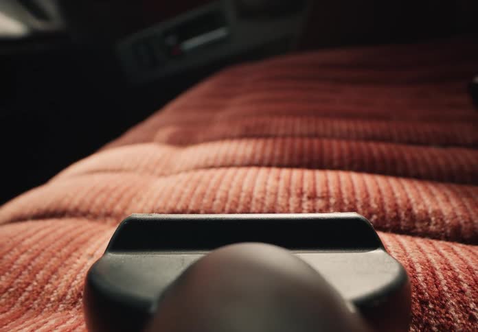 POV of a vacuum cleaner cleaning the red velour seats inside a classic car