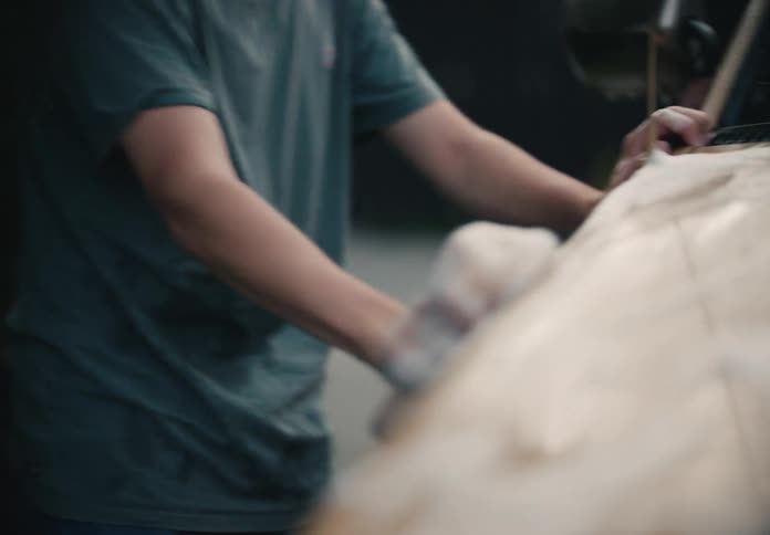A teenage boy thoughtfully soaps up the hood of a car and then wipes his face in slow motion