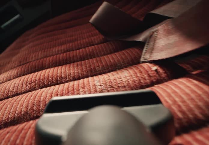 A first-person view shows a handheld vacuum cleaner being used to clean the red fabric interior of a vintage car