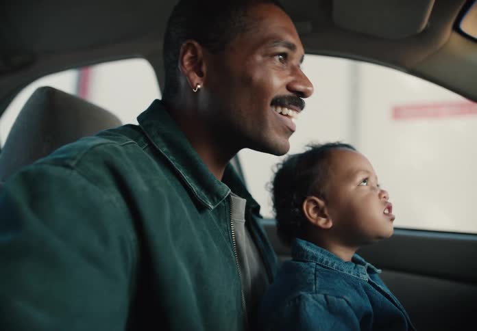 A loving African American father and his young son share a happy moment together while sitting in the car