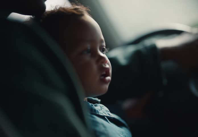 A close-up of a toddler watching attentively as their father drives them in the car