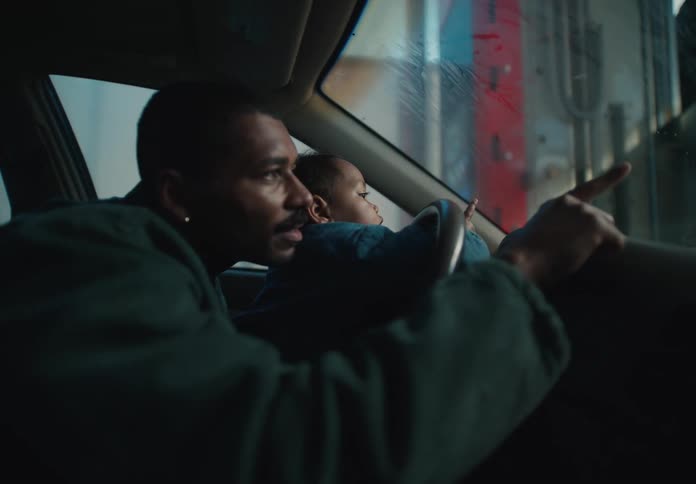 A happy African American father holds his baby boy on his lap while they go through an automatic car wash together