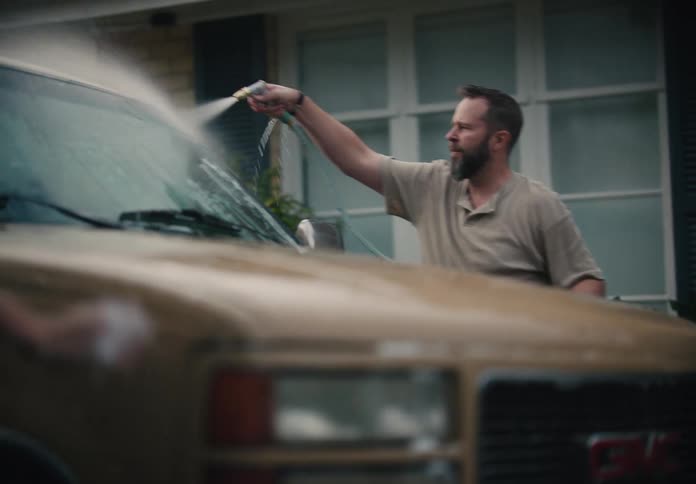 Father and son wash a truck in their driveway in slow motion