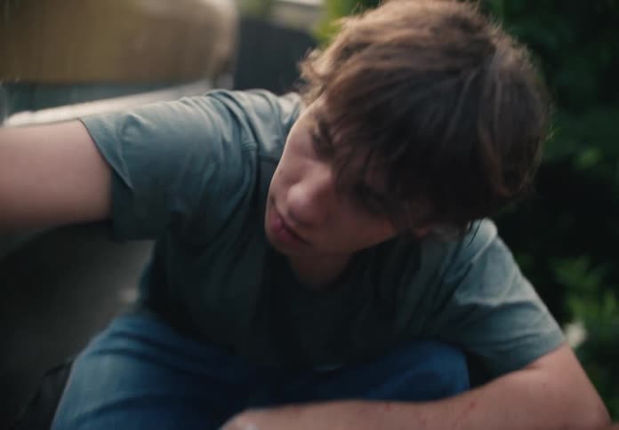 Close-up shot of a teenage boy diligently cleaning the wheel of a car with soap and a sponge in slow motion
