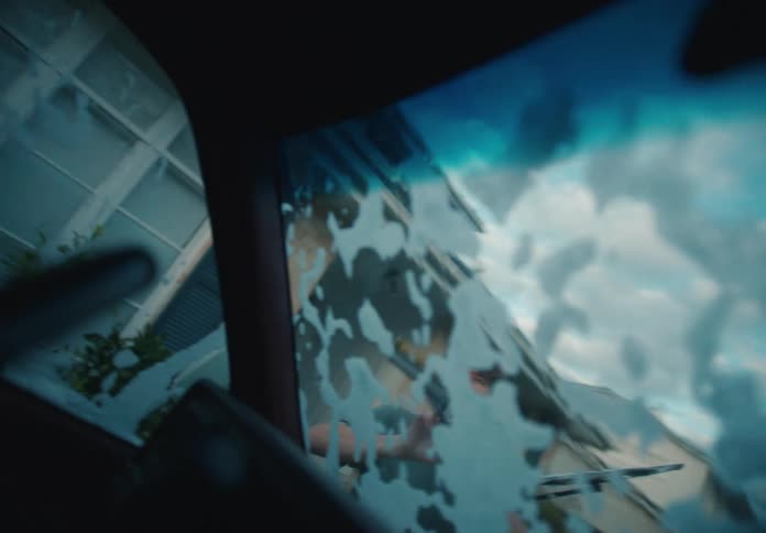 Interior perspective of a father and son working together to clean a soapy car windshield with squeegees at dusk