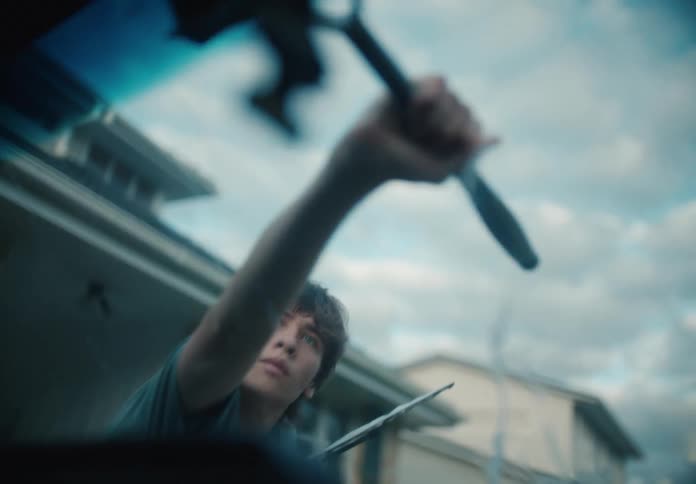 Focused young man diligently cleans a car windshield with a squeegee in a slow-motion, point-of-view shot