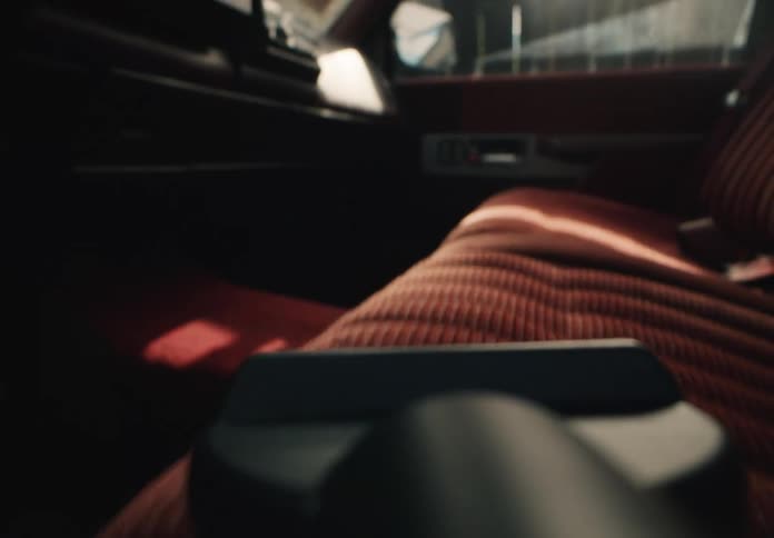 A close-up, first-person view of vacuuming the red velvet ribbed seats of a vintage car interior in slow motion