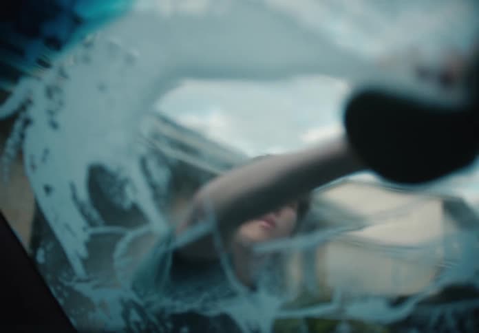 Interior car view of a young man thoughtfully washing the sudsy windshield with a sponge in slow motion