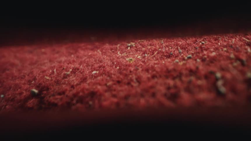 Extreme close-up slow-motion shot of a vacuum cleaner thoroughly cleaning dirt and pebbles from a red car floor mat