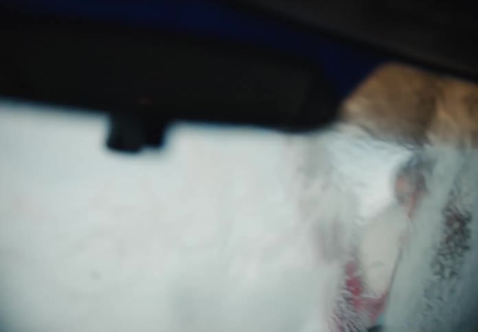 A blurry point-of-view from inside a car as it goes through an automatic car wash, with soap and water obscuring the windshield