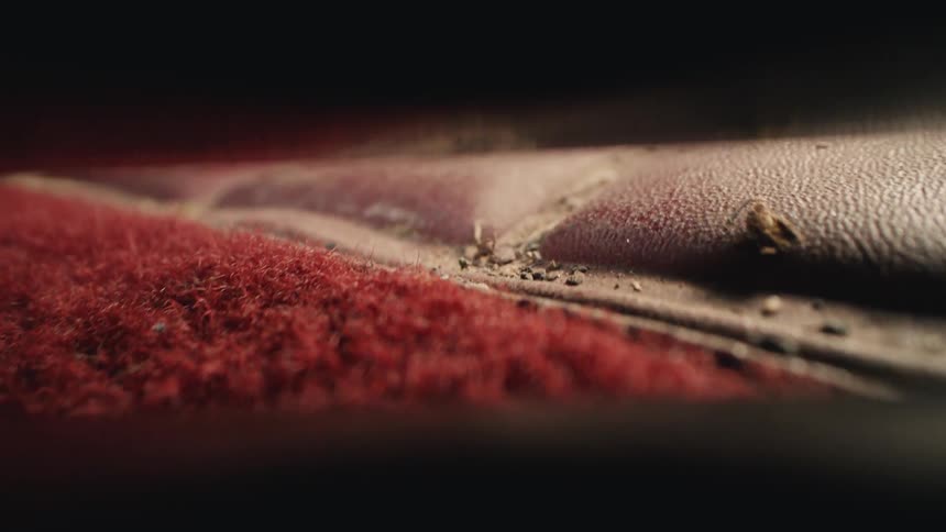 Satisfying macro close-up of a vacuum cleaner sucking up dirt and debris from a dirty red car interior
