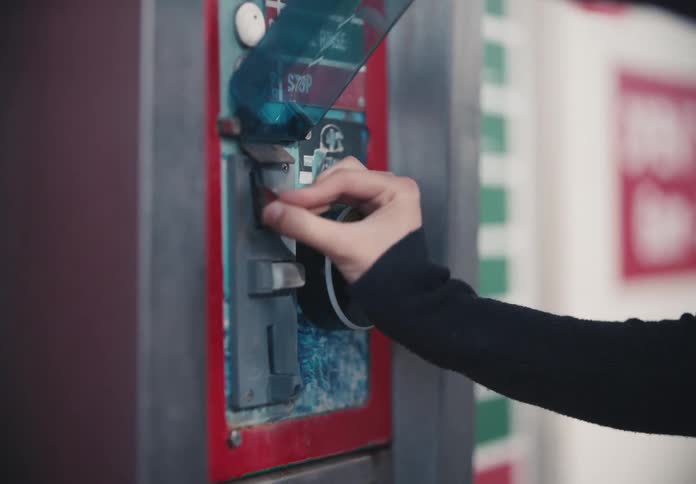 A close-up shot of a person inserting a coin into a self-service payment station at a car wash