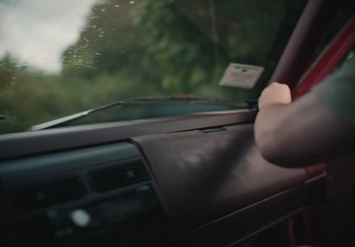 Close-up of a man's hands using a cloth to meticulously clean the dashboard of an older model car