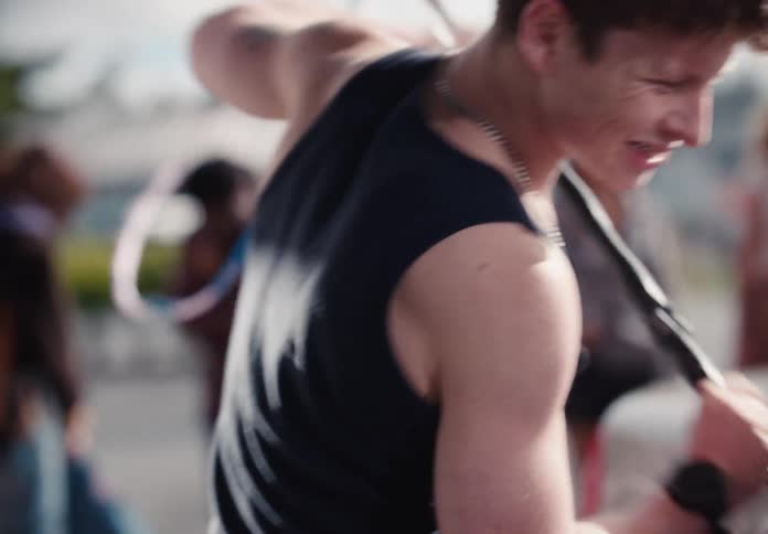 Slow motion shot of a muscular young man enjoying himself as he washes a car covered in pink soap