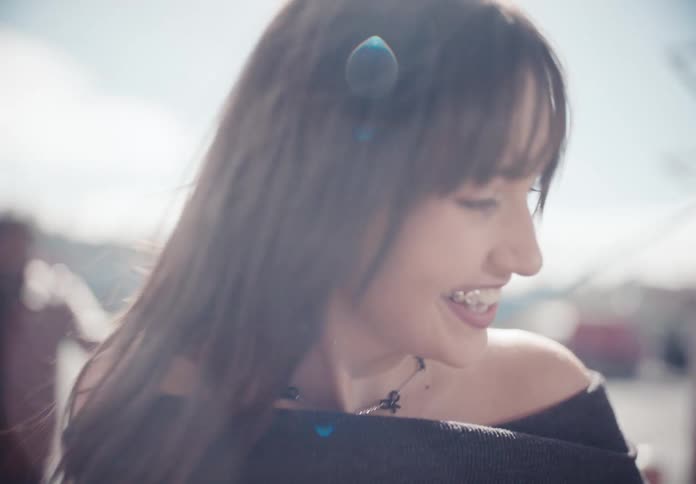 A close-up slow motion shot of a smiling young woman with dark hair enjoying a bright sunny day outdoors
