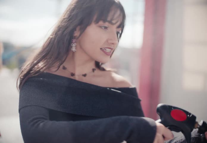A stylish young woman smiles as she uses a high-pressure water gun at a car wash in slow motion