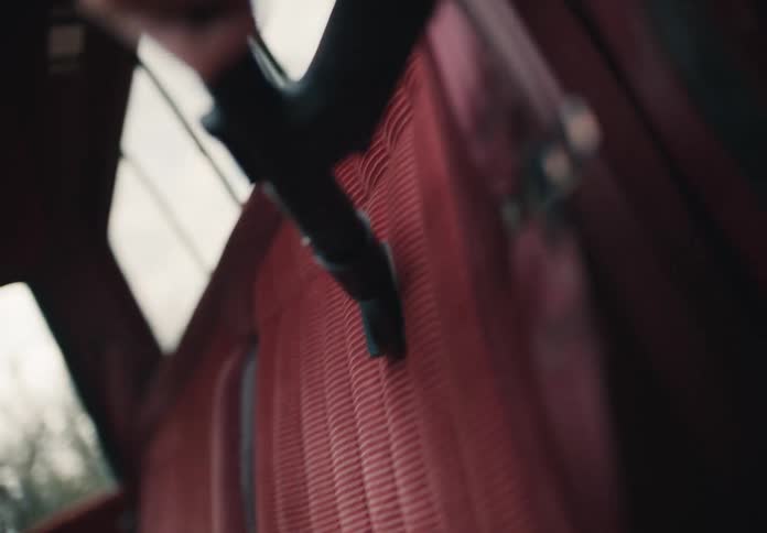 A person vacuums the red corduroy upholstery seats inside of a vintage vehicle