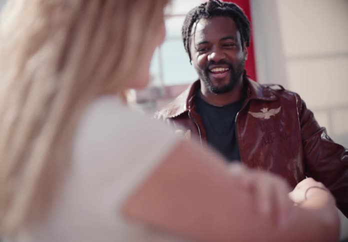 A beautiful young woman and her handsome boyfriend laugh and talk together on a sunny day