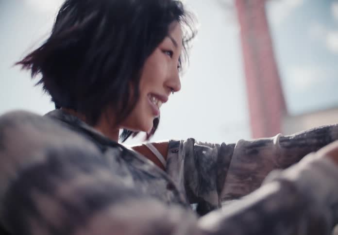A sun-drenched slow-motion close-up of a smiling young Asian woman enjoying a beautiful day