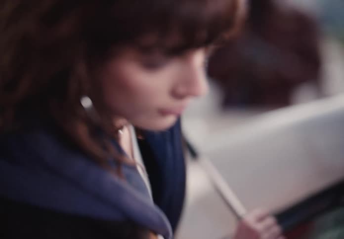 A determined young woman rows a boat, her focused expression captured in a shaky, intimate close-up shot