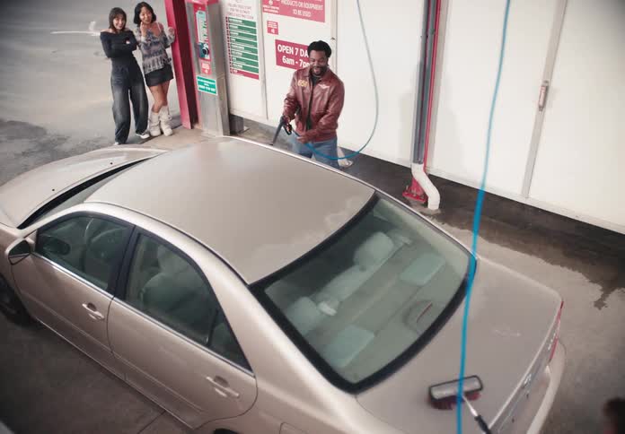 High angle shot of a diverse group of young friends having fun and washing a car together at a self-service car wash
