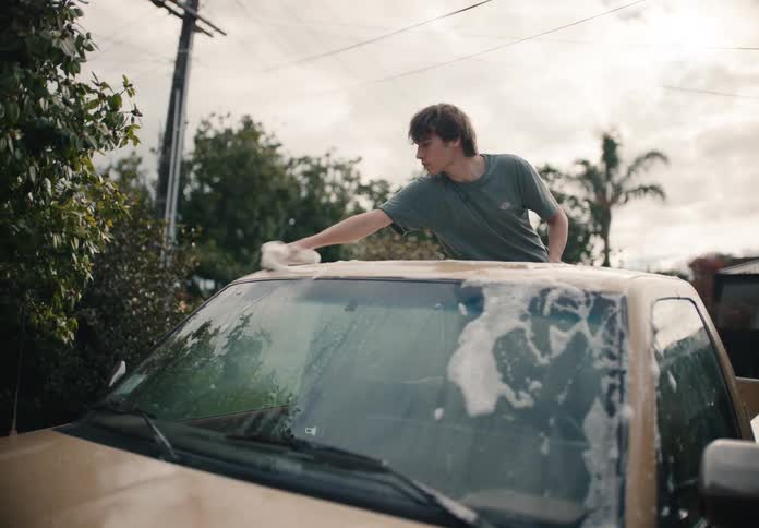 A father and his teenage son work together to wash their pickup truck in the driveway in slow motion