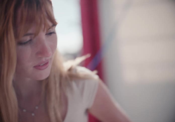 A dreamy, soft-focus close-up shot of a pensive young woman with blonde hair looking off into the distance