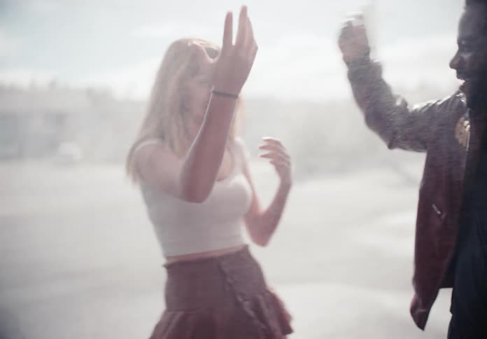 Slow motion shot of a joyful young couple laughing and dancing while playfully spraying water at a self-service car wash