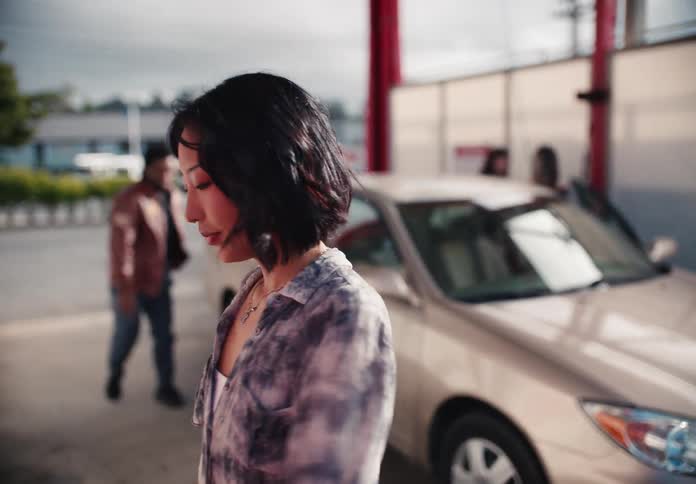 A stylish young Asian woman gets out of her car with friends and pays at the terminal to begin washing their car at a self-service car wash