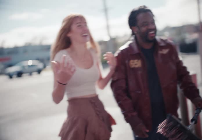 A carefree couple laughs and dances together in slow motion while getting soaked at a self-service car wash