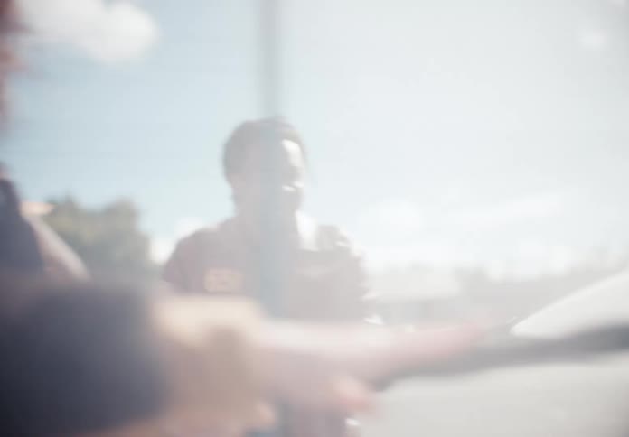 Dreamy, soft-focus slow motion of a happy couple laughing and playing with pressure washers at a self-service car wash on a sunny day